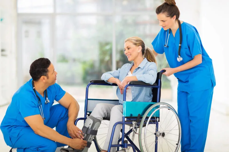 Two nurse helping a patient on a wheelchair